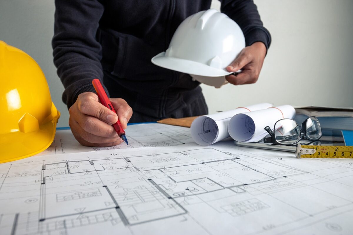 Photo d’un ingénieur de construction travaillant sur plan avec casque de chantier en main